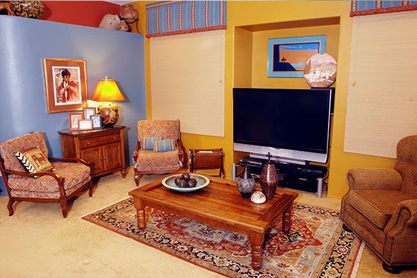 family room with rug in the middle and blue, yellow, and tan colored walls. 