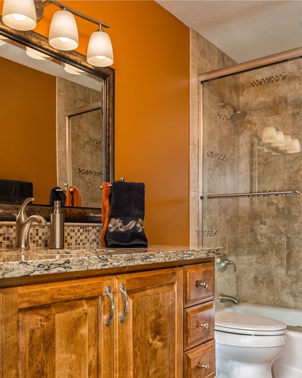 Dark orange walls with wooden drawers under a marbled sink. 