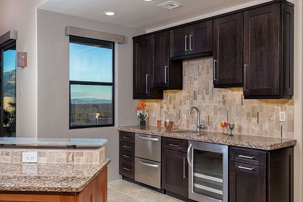 Dark wooden kitchen cabinets and marble counter tops. 