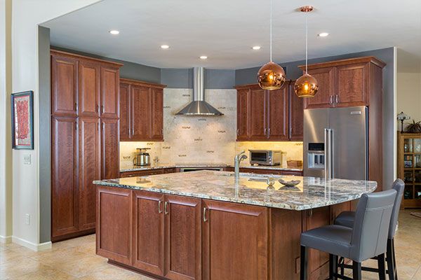 Kitchen with grey seats on one side of island. 