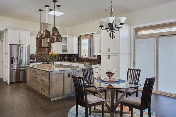 Kitchen with round glass table and white cabinets. 