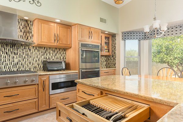 Light wood colored cabinets with tile kitchen wall. 