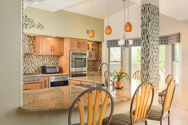Light green walls with light wooden colored cabinets and marbled kitchen sink top. 