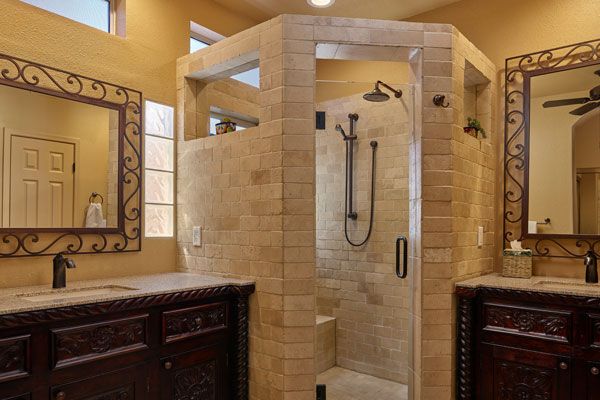 Brick walls around shower with dark wooden cabinets. 