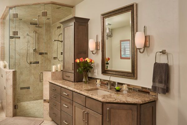 Bathroom with glass shower doors and wooden cabinets. 