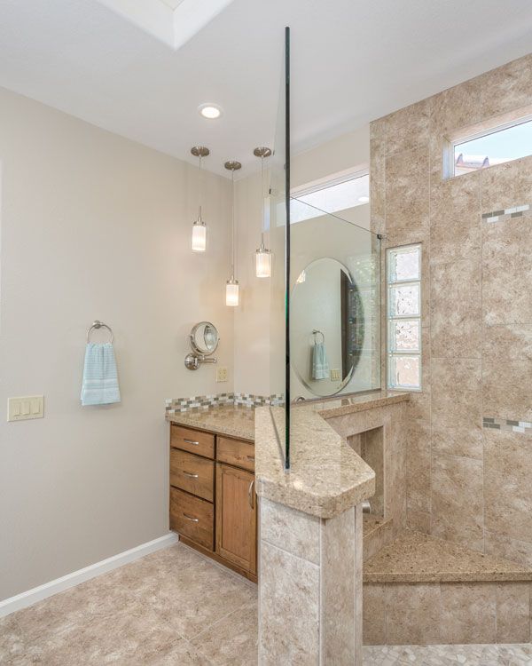 Light colored walls with marbled shower walls with glass on top half. 