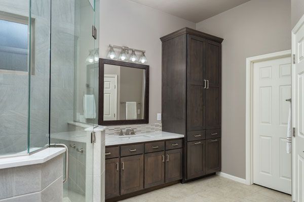Dark wooden cabinets with glass shower walls in a bathroom. 